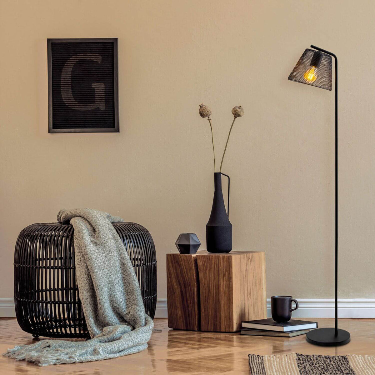 Lampadaire noir dans un salon beige, panier tressé et vase en bois