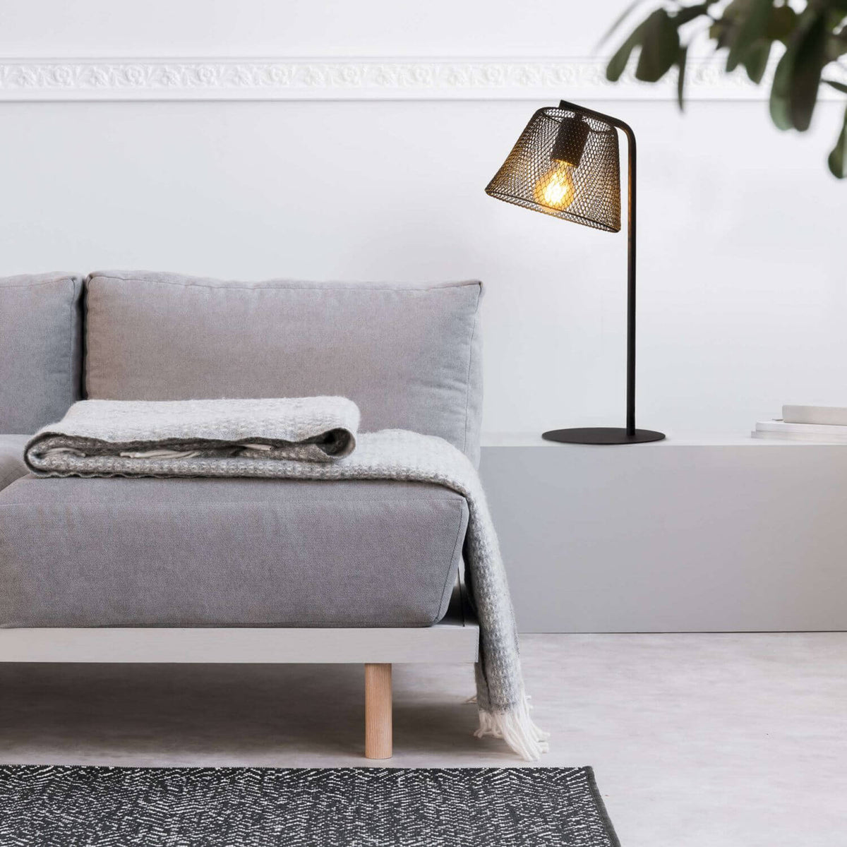 Mise en ambiance salon : lampe posée sur console derrière un canapé gris