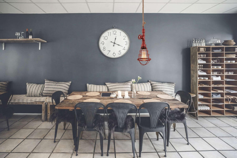 Suspension rouge allumée au-dessus d'une table rustique dans une salle à manger grise
