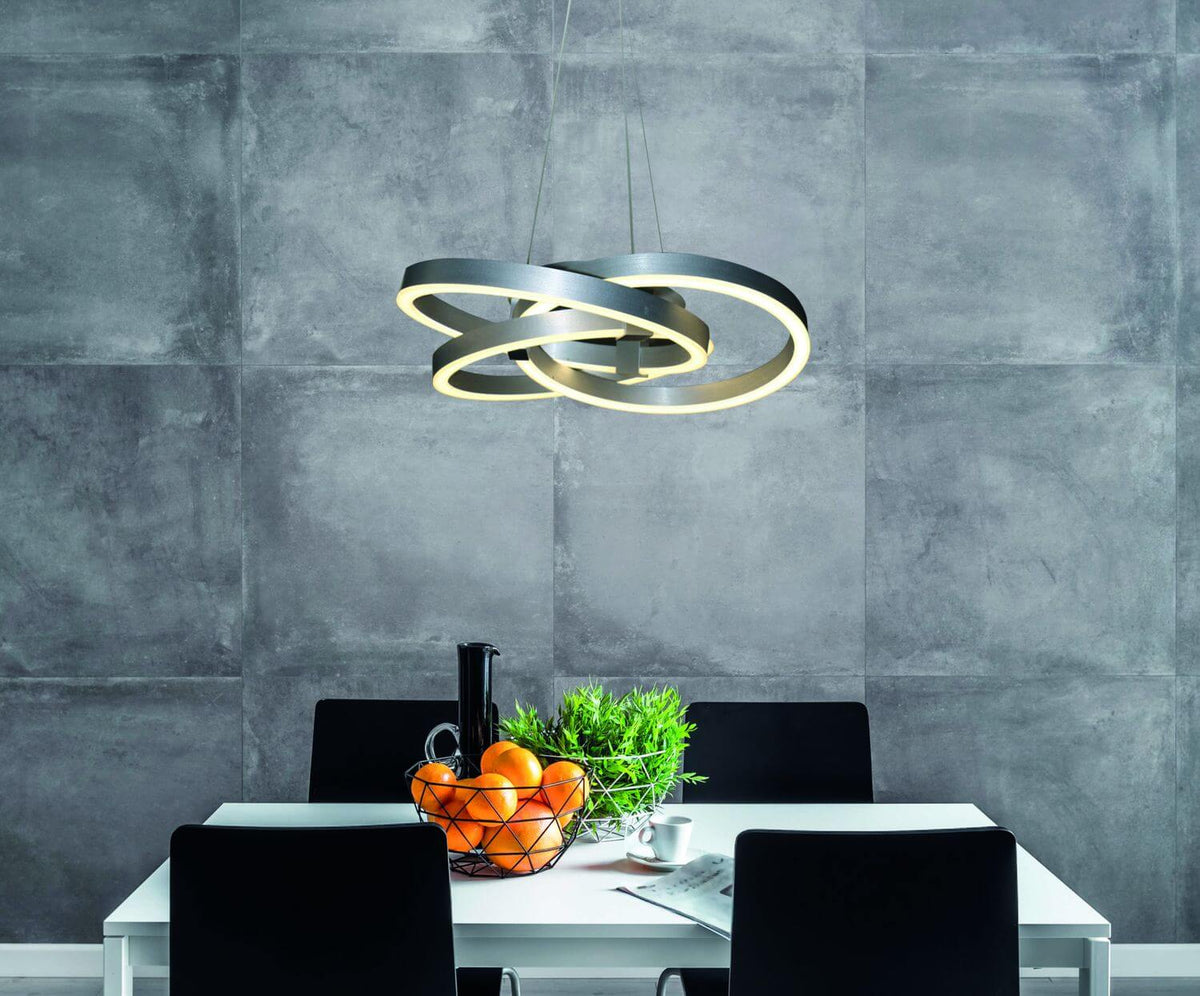 Luminaire suspendu éclairant une salle à manger, mur béton et chaises noires.