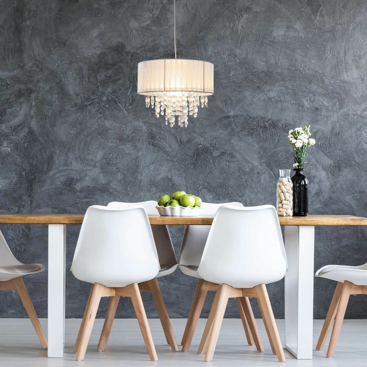Vue en situation sur fond mural gris, suspension allumée éclairant une table en bois.