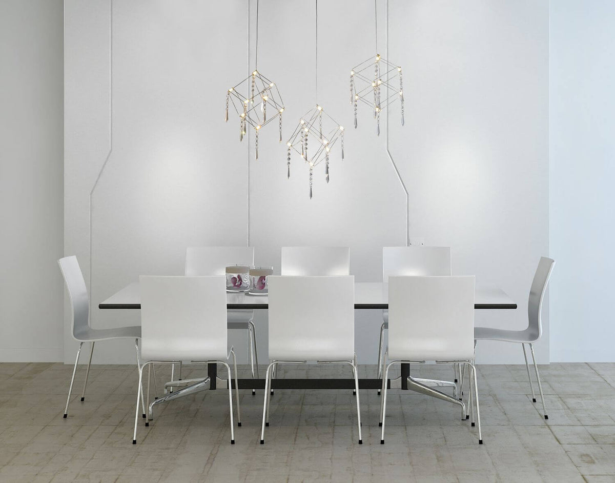 Suspension installée au-dessus d'une table de salle à manger avec chaises blanches.