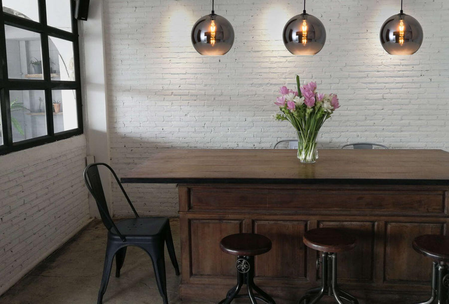 Trois suspensions boule en verre fumé éclairées au-dessus d'un comptoir en bois