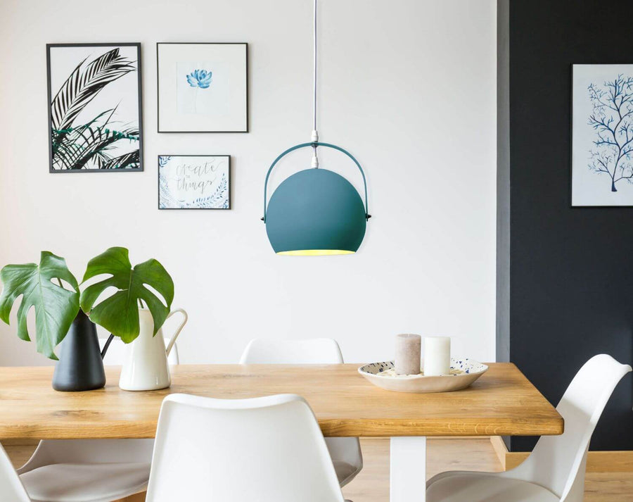 Vue rapprochée du luminaire bleu canard suspendu, table dressée et cadre mural.