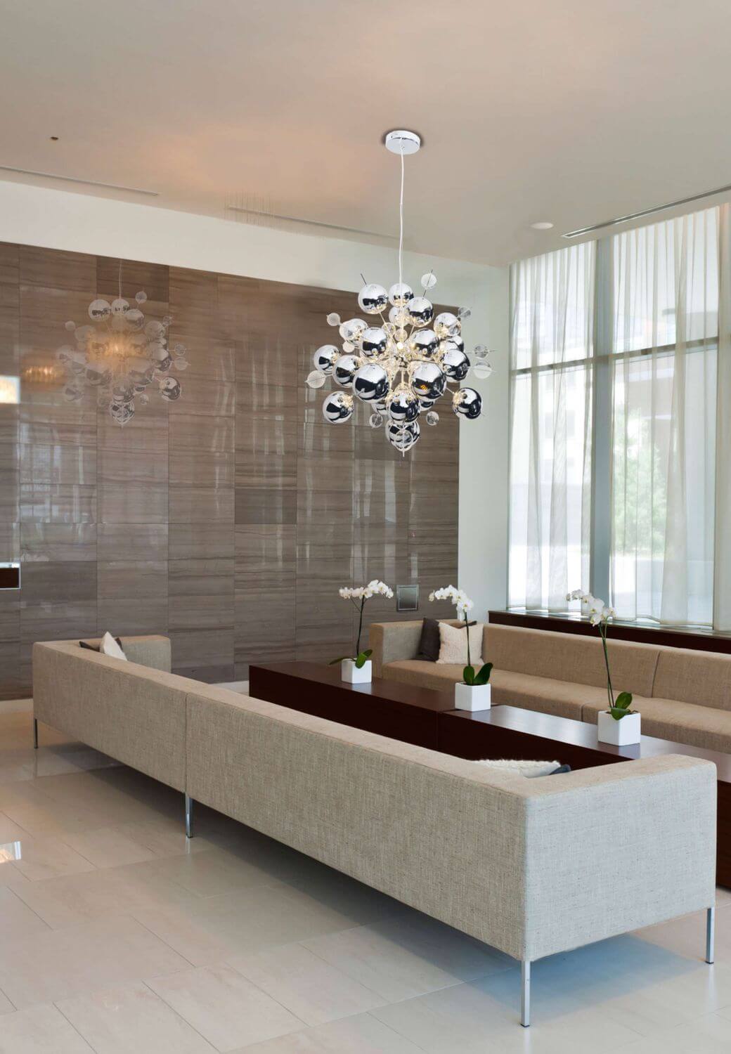 Vue en ambiance du lustre chrome au-dessus d'un salon clair et réfléchissant