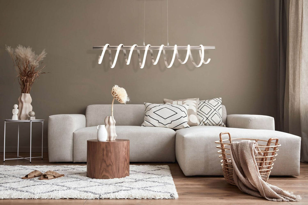 Suspension allumée dans un salon beige avec canapé d'angle et tapis.