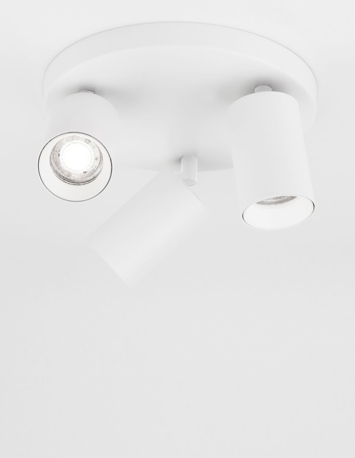 Plafonnier blanc à trois spots cylindriques orientables vu depuis le plafond
