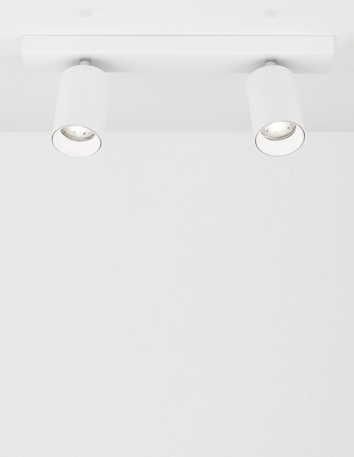 Plafonnier blanc à deux spots cylindriques orientables, vue de face sur fond clair