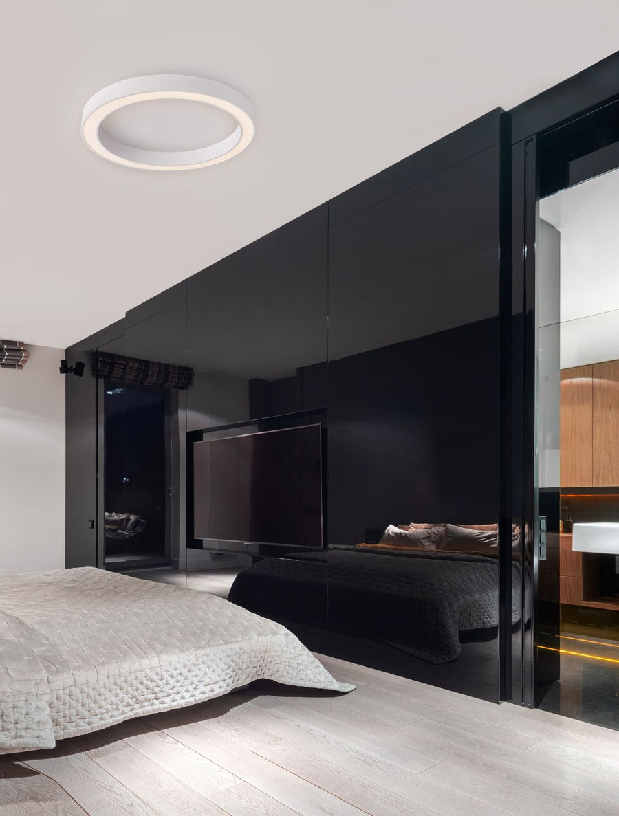 Plafonnier blanc circulaire installé au plafond d'une chambre contemporaine sombre