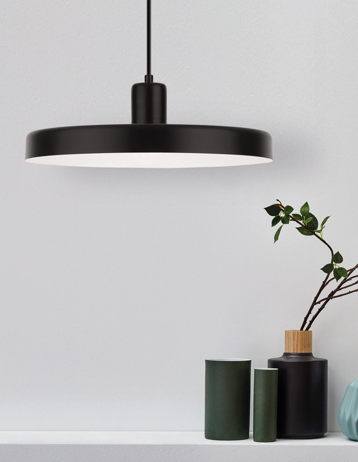 Suspension noire au-dessus d'une étagère avec vases et branches vertes