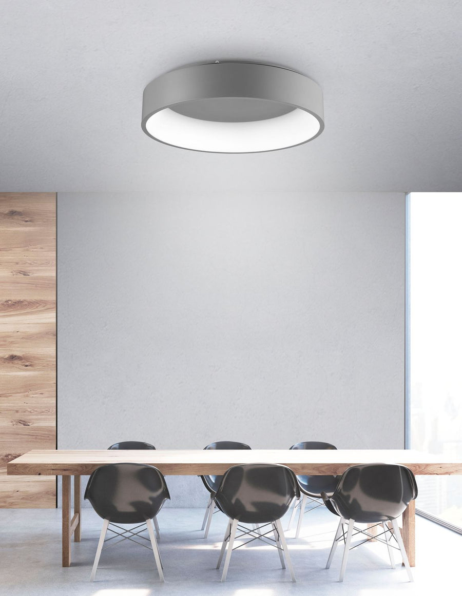 Plafonnier gris fixé au plafond au-dessus d'une table à manger en bois clair