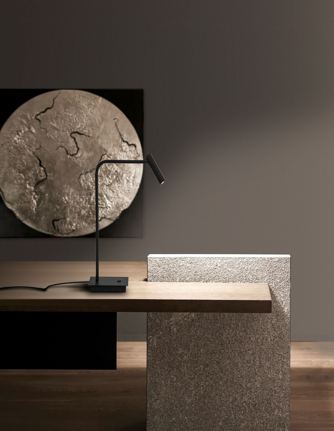 Lampe noire posée sur un bureau en bois, mise en ambiance épurée