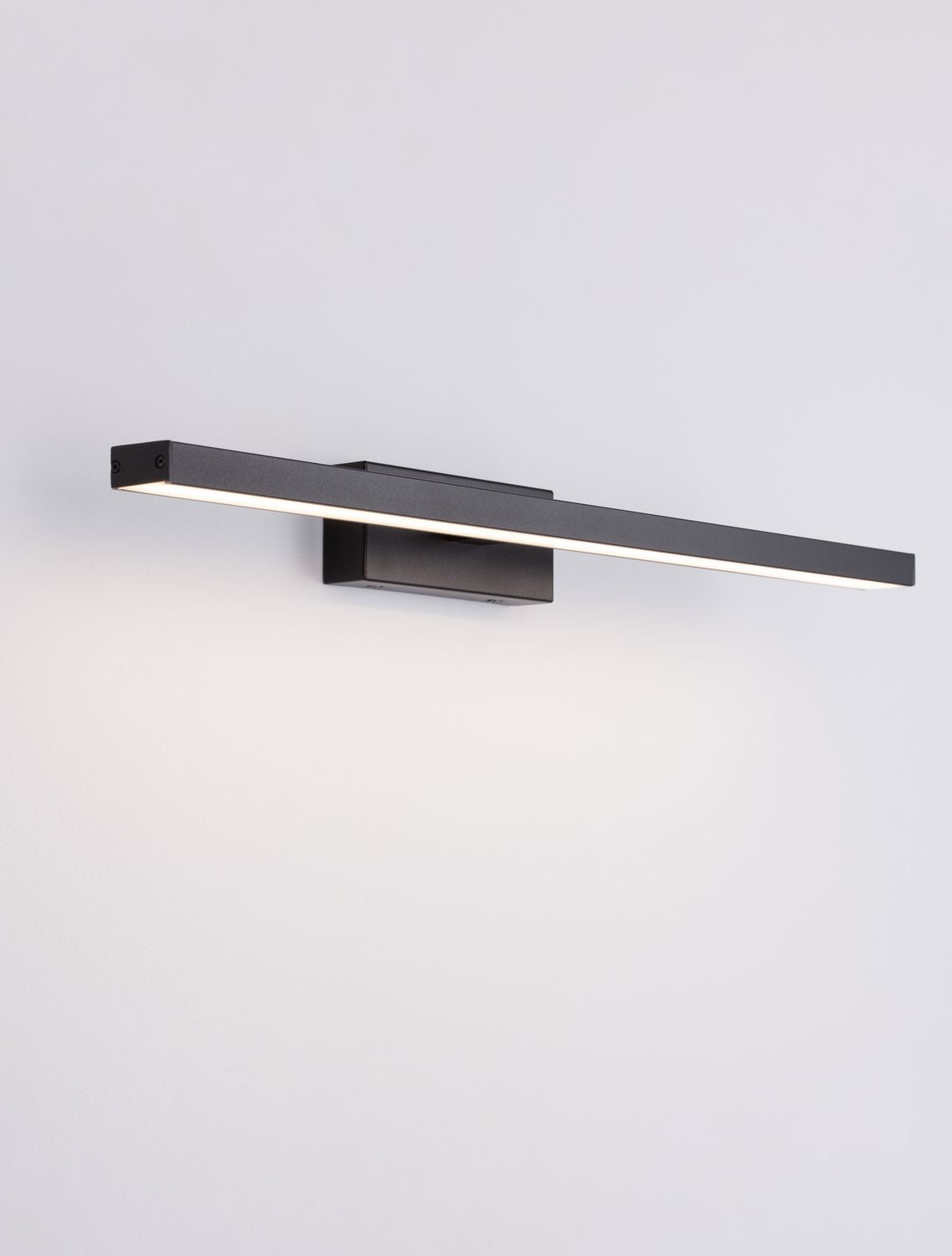 Vue trois quarts du luminaire allumé, longue bande LED en lumière rasante