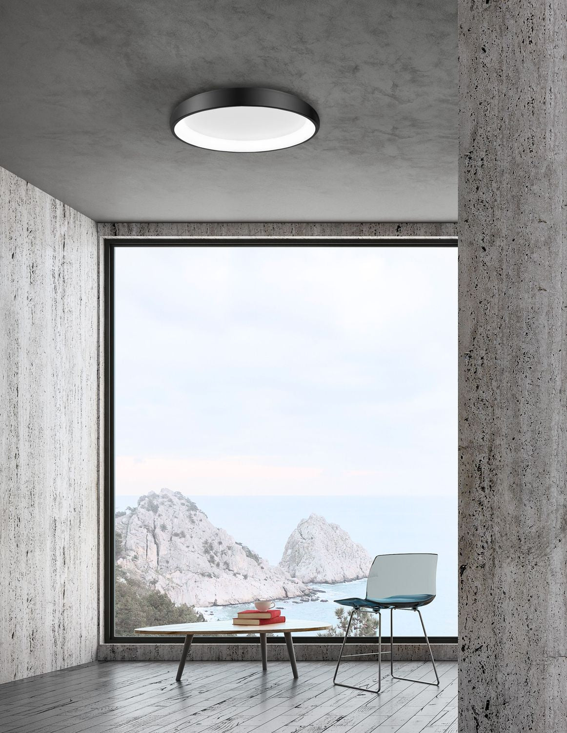 Plafonnier noir allumé au plafond d'un salon béton ouvert sur la mer