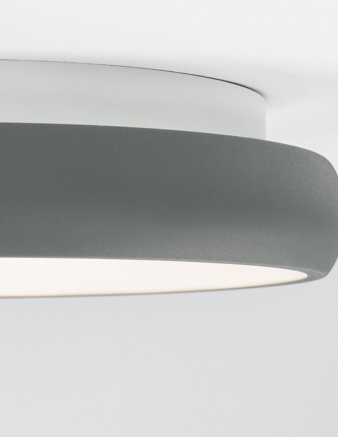 Gros plan sur l'épaisseur de l'anneau gris fixé contre le plafond blanc