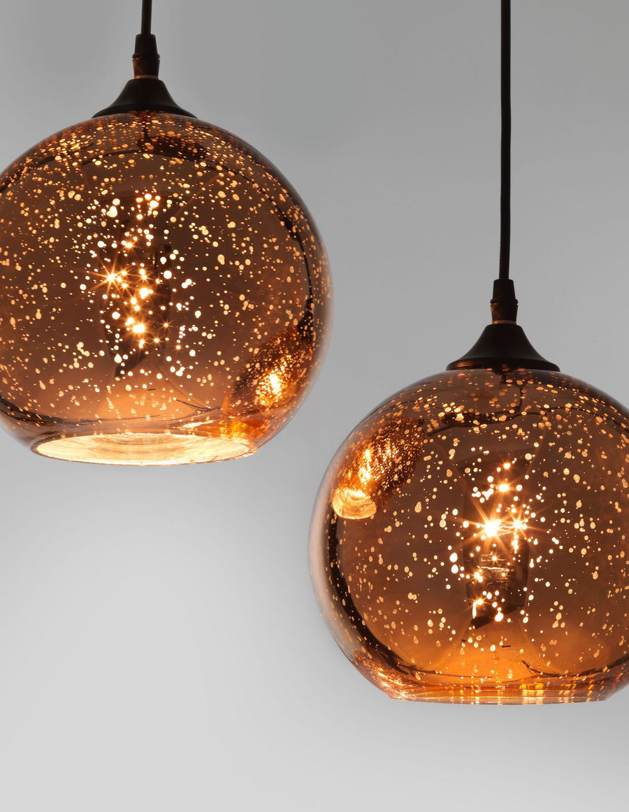 Détail rapproché des deux globes en verre moucheté et lumière chaude.