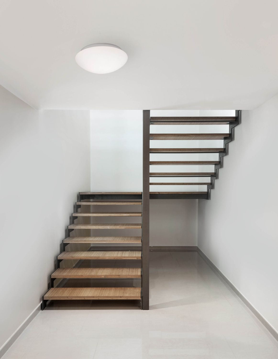 Plafonnier rond blanc installé au plafond d'une cage d'escalier moderne