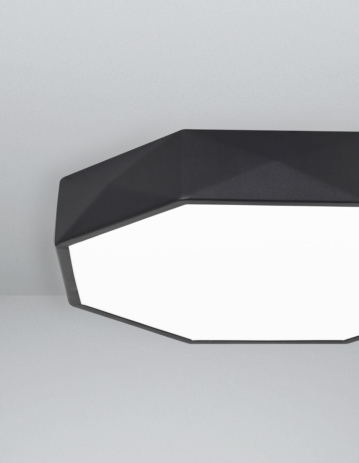 Gros plan du bord facetté noir et du diffuseur blanc du plafonnier octogonal