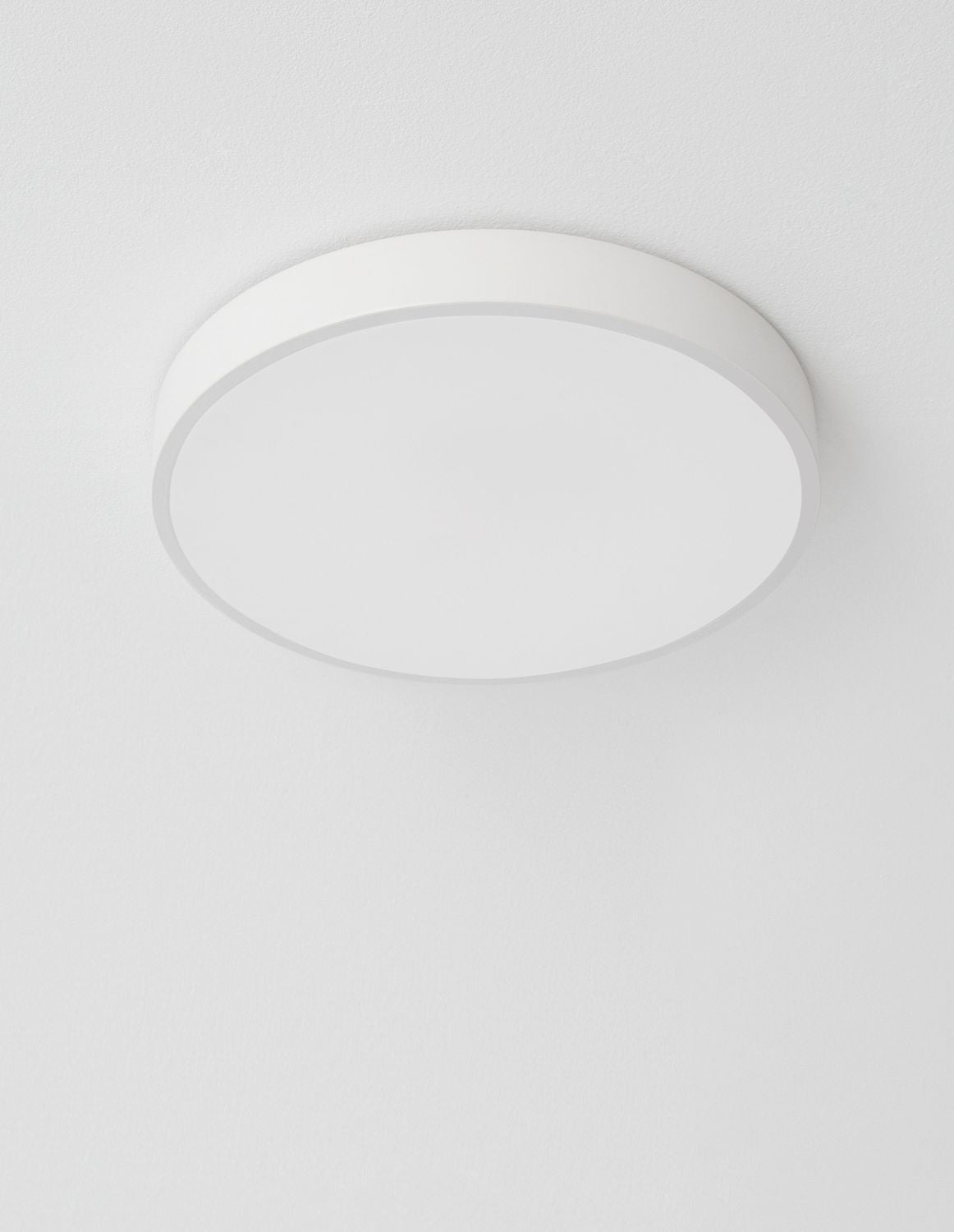 Plafonnier blanc vu de dessous, fixé au plafond, lumière éteinte, cadrage rapproché