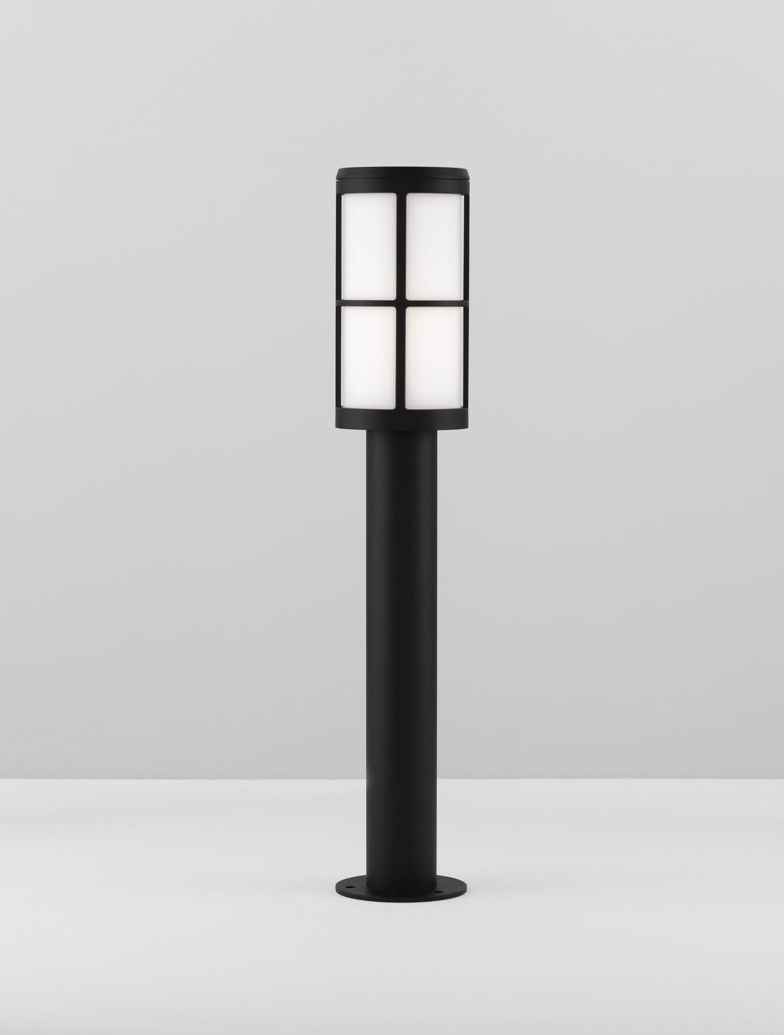 Luminaire présenté debout sur un plan gris, base circulaire et mât cylindrique