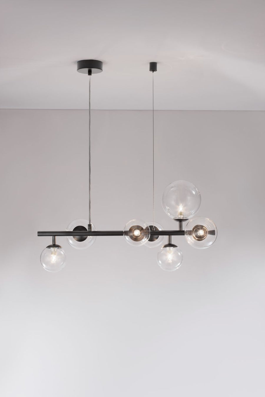 Luminaire suspendu vu de face, ampoules allumées dans les globes transparents