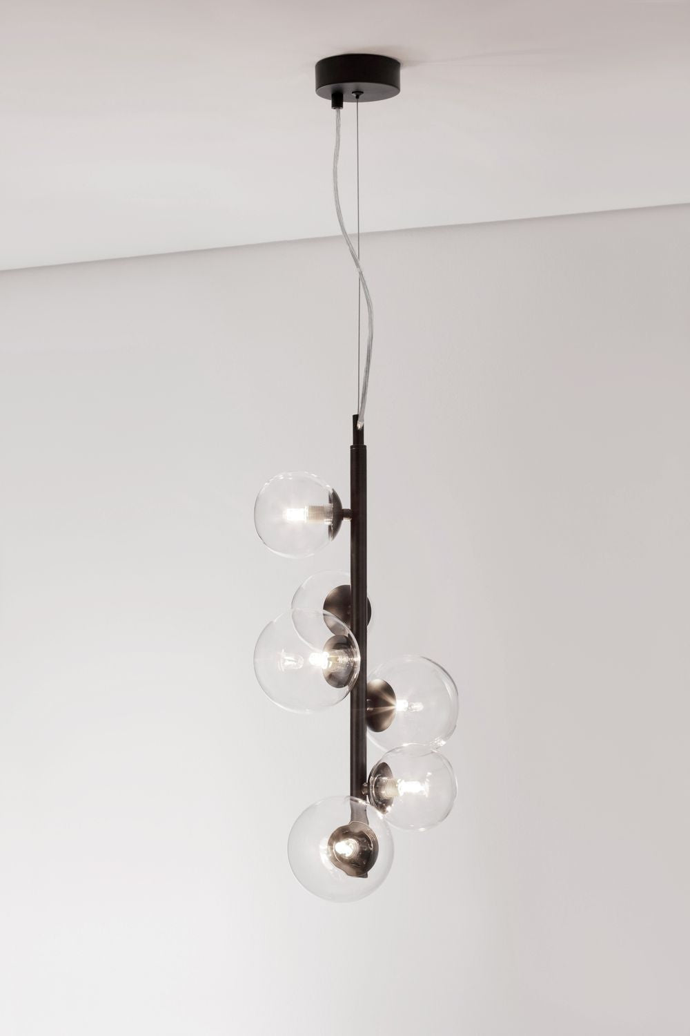 Luminaire allumé sur fond clair, ampoules visibles à l'intérieur des globes transparents