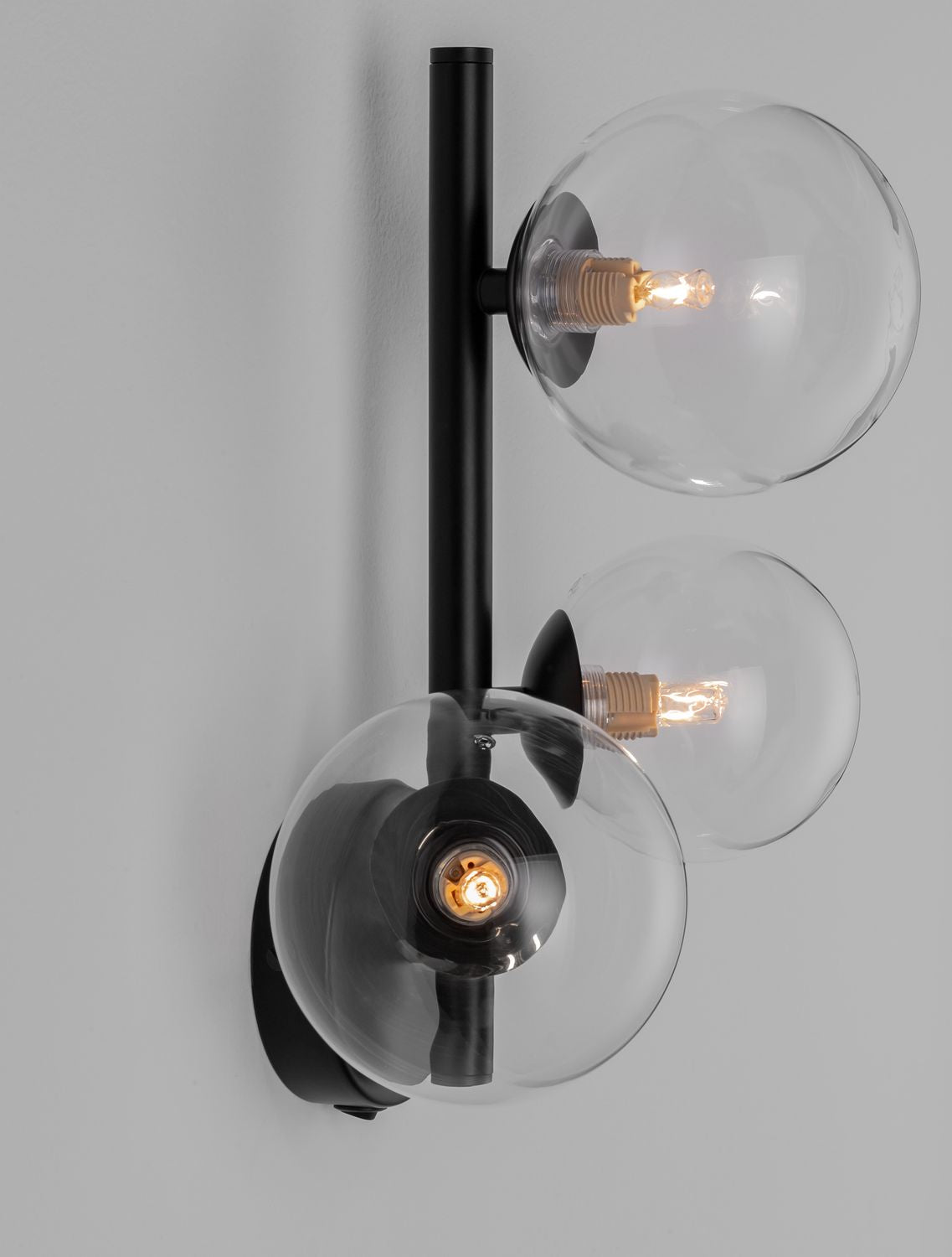 Vue de profil dévoilant le bras vertical noir et les globes fixés au mur.