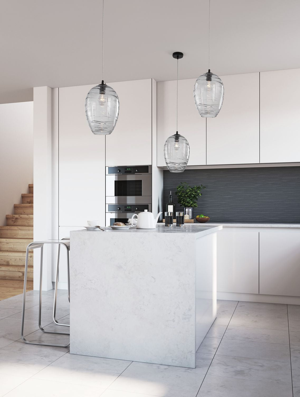Trois suspensions en verre transparent suspendues au-dessus d'un îlot de cuisine blanc et lumineux