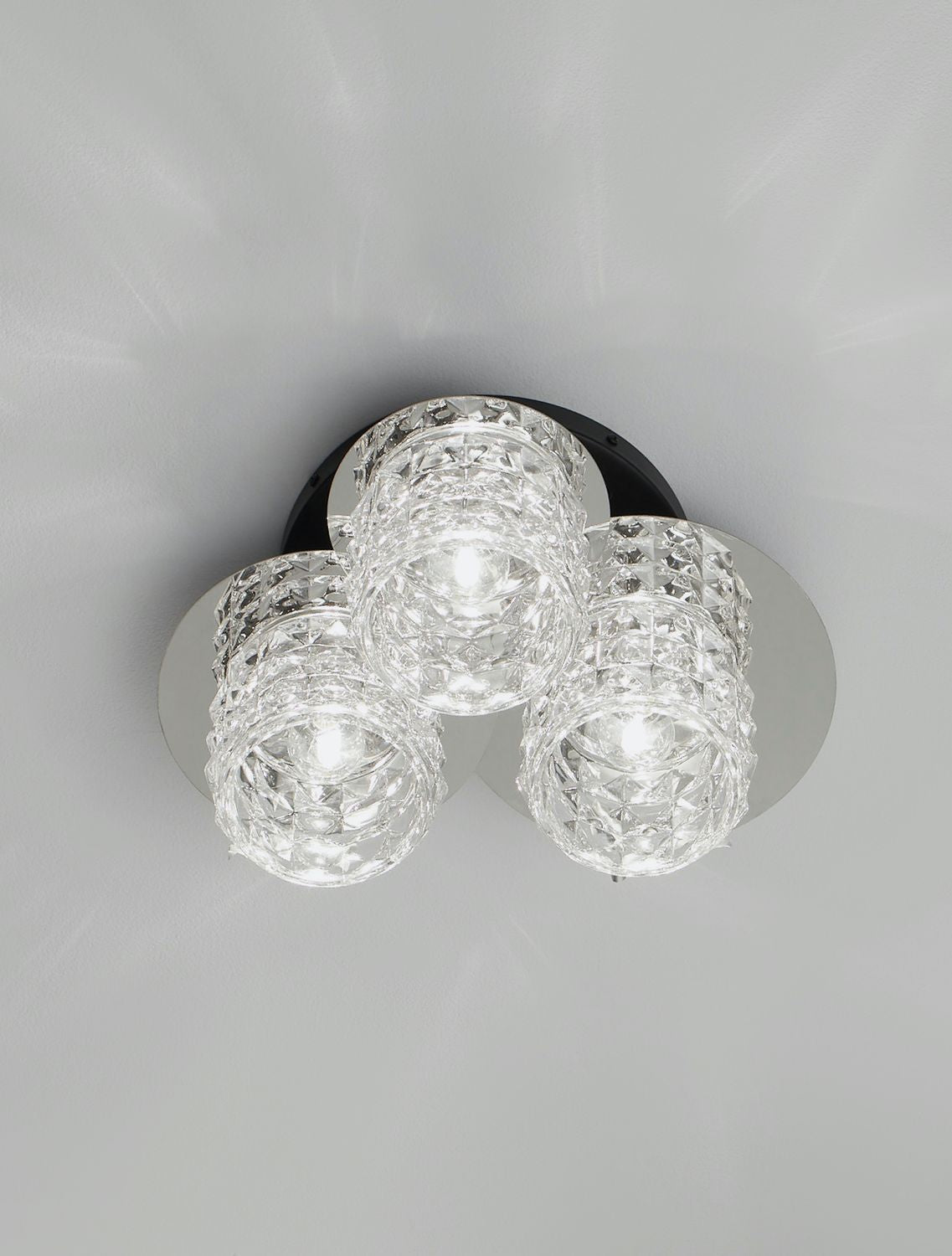 Plafonnier allumé, les trois cylindres de verre diffusent une lumière éclatante