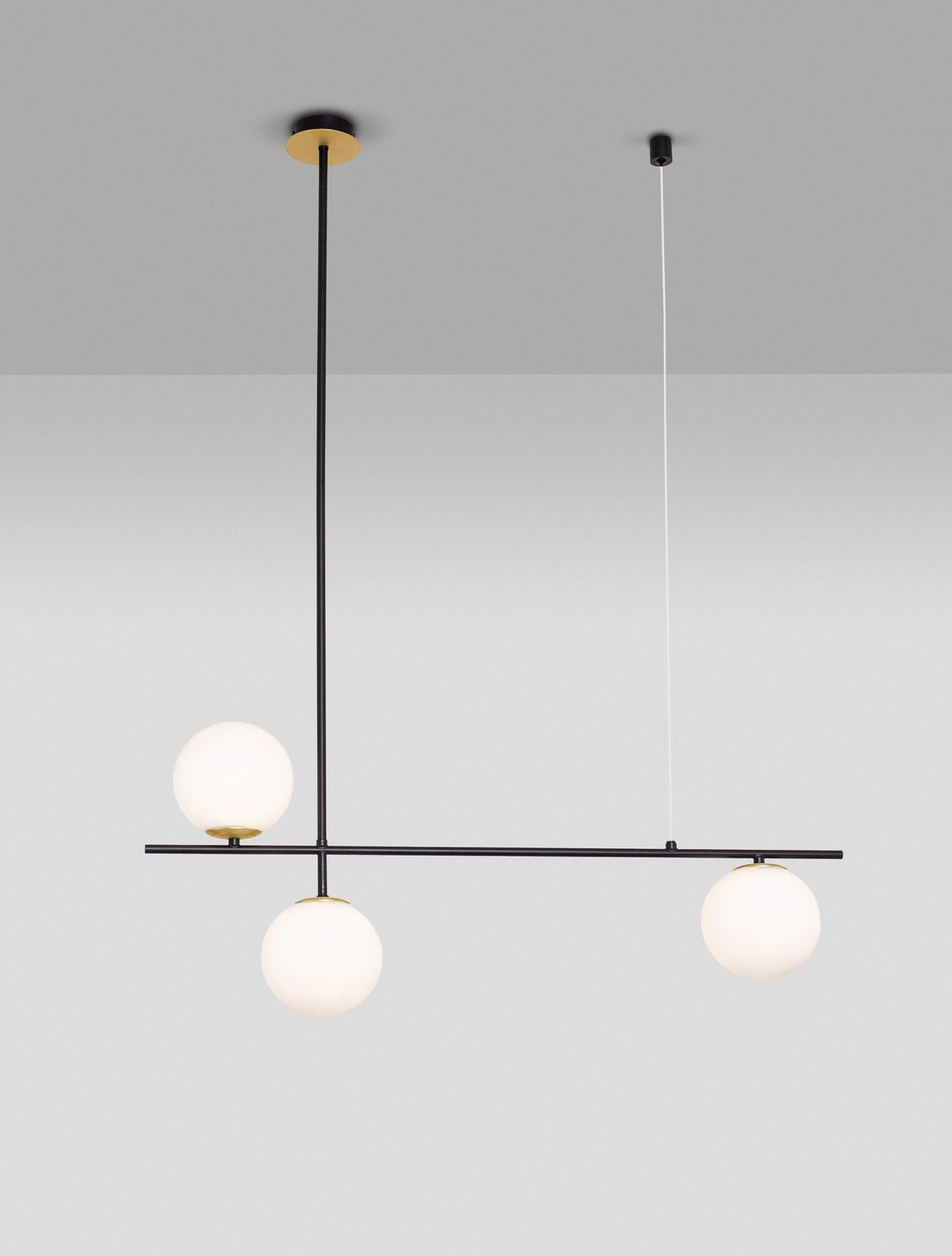 Suspension dorée à trois globes de verre opalin sur barre noire, vue de face