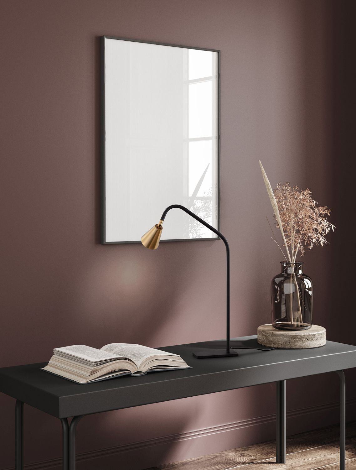 Lampe à poser noire et laiton posée sur une console, livre ouvert et vase décoratif.