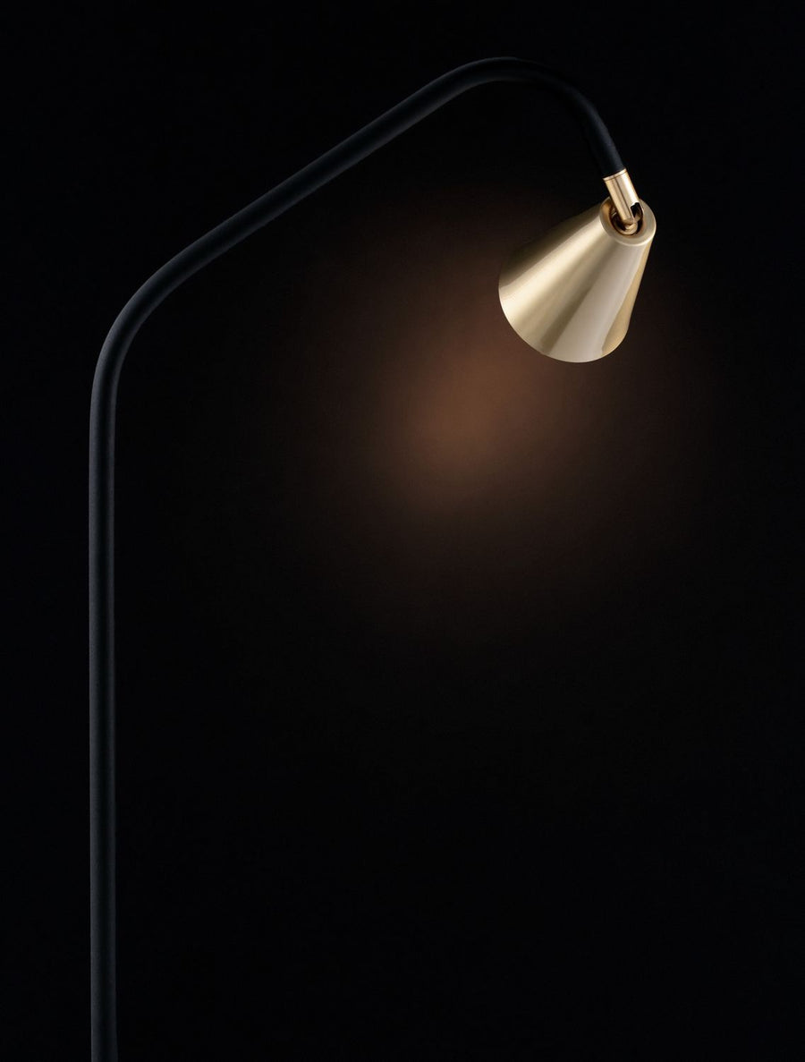 Détail de l'abat-jour laiton éclairé dans l'obscurité, diffusant une lumière chaude.