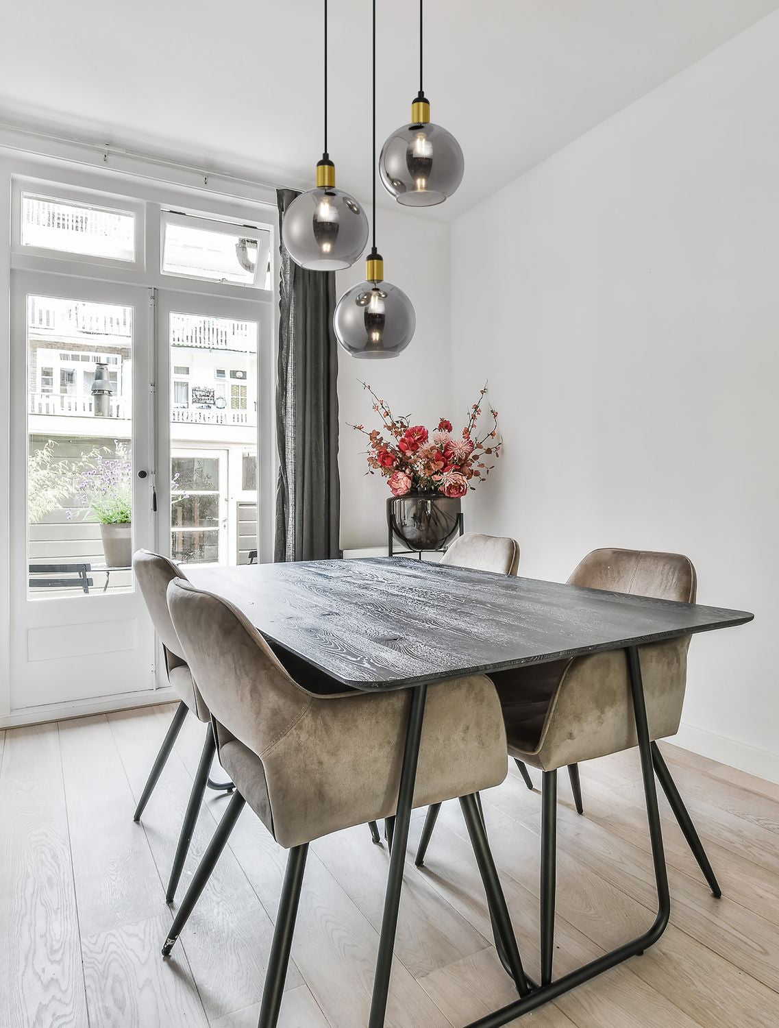 Suspension à trois globes fumés installée au-dessus d'une table de salle à manger lumineuse