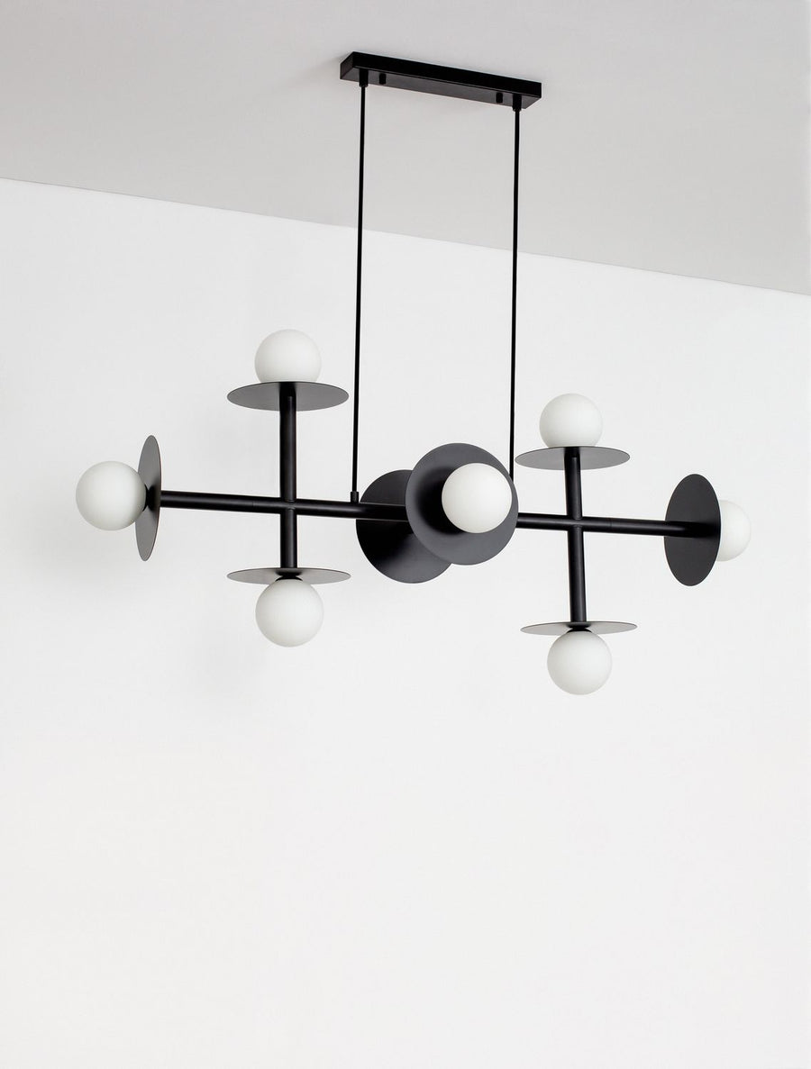 Suspension noire présentée contre un mur blanc, structure géométrique et globes en verre.