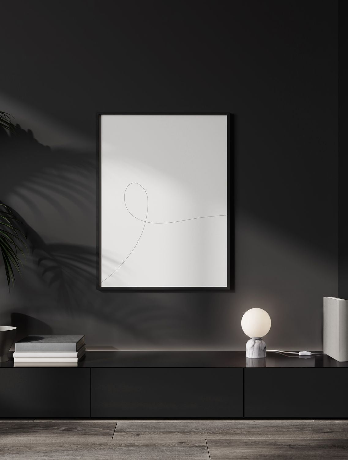 Lampe posée sur un meuble noir devant un cadre blanc, mise en ambiance sombre.
