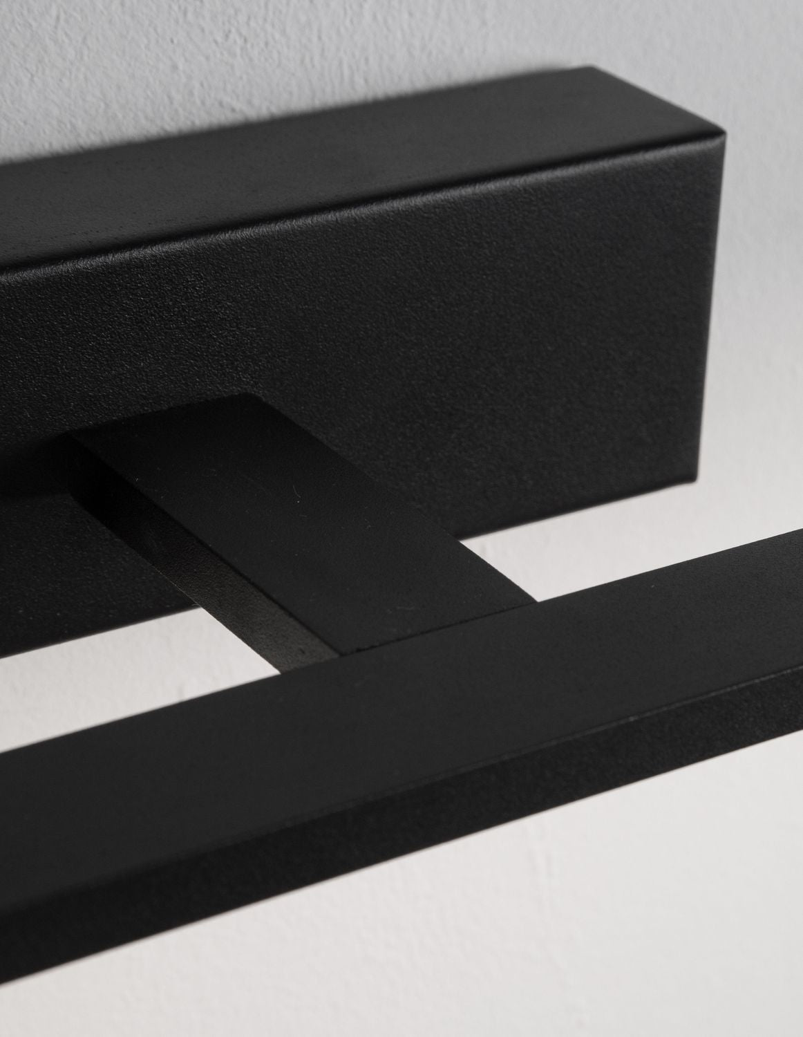 Détail rapproché de la finition noire mate et de la jonction entre barre et socle
