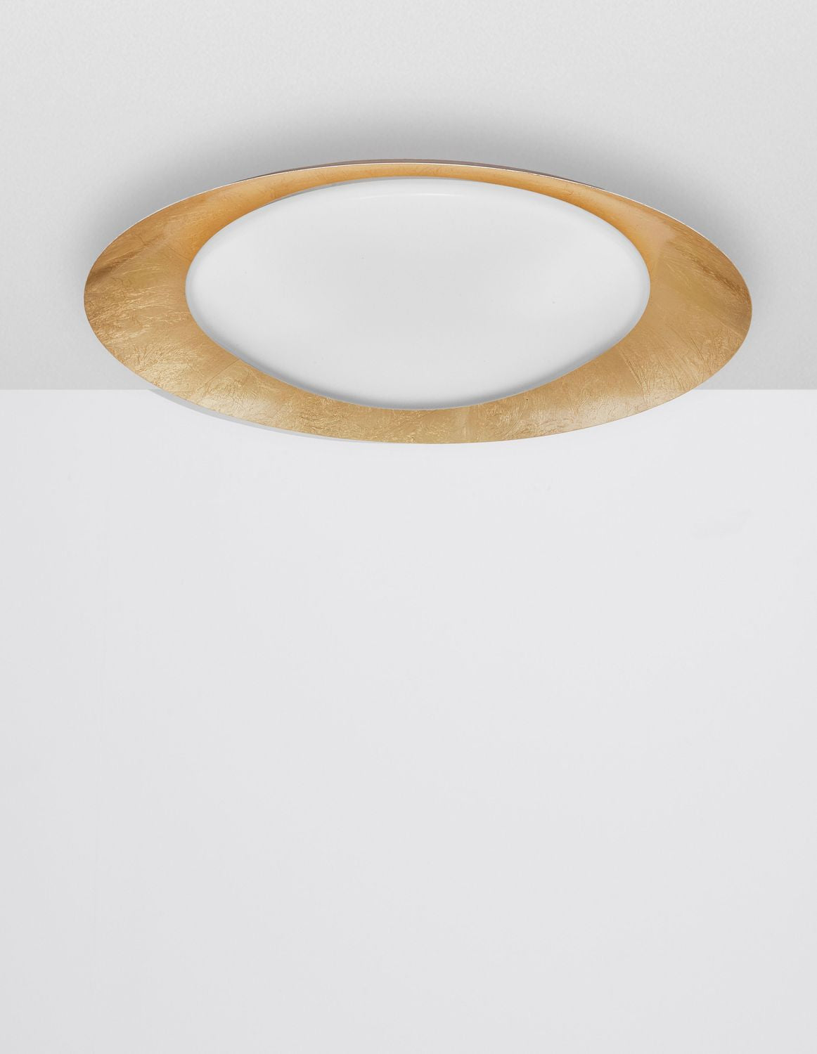 Vue frontale du plafonnier allumé, halo lumineux diffusé sous le plafond blanc