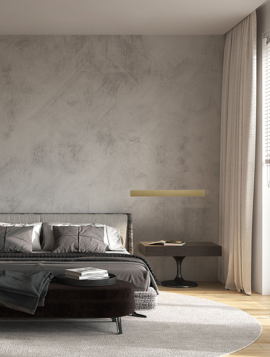 Applique dorée fixée au mur au-dessus d'une table de chevet dans une chambre grise