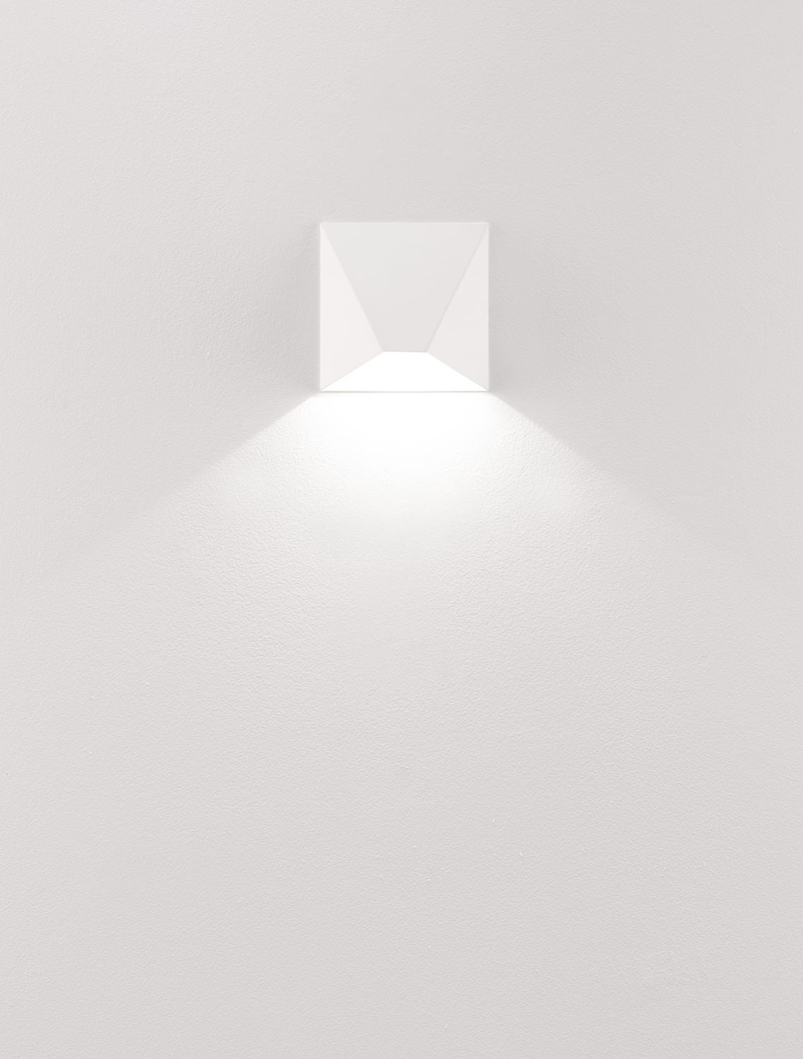 Luminaire blanc allumé projetant un cône de lumière vers le bas