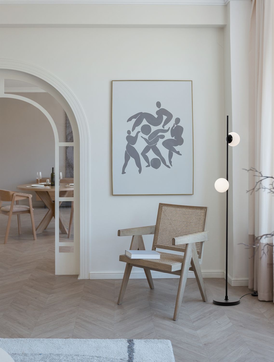 Lampadaire noir allumé dans un salon, près d'un fauteuil en cannage