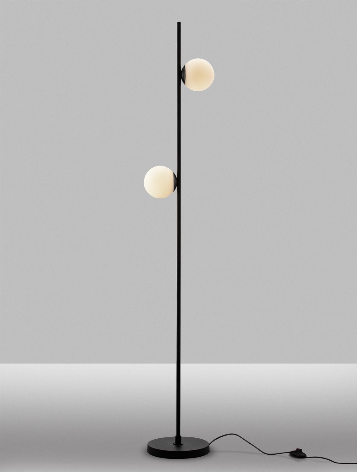 Lampadaire allumé sur fond gris, globes diffusant une lumière chaude