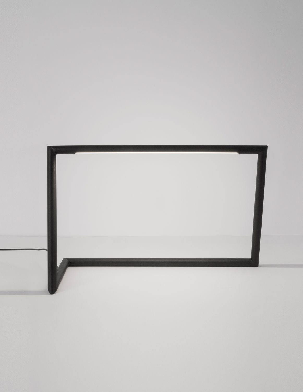 Lampe à poser noire de face, cadre rectangulaire ouvert sur fond clair