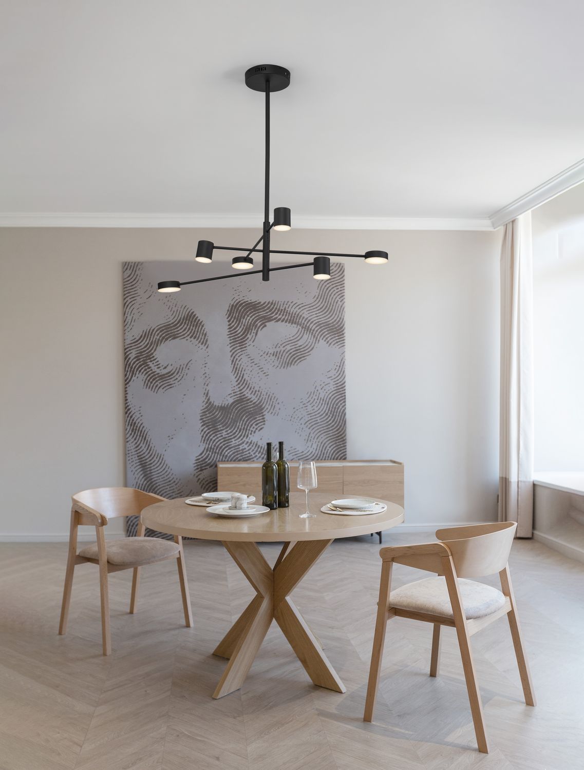 Suspension noire à huit bras au-dessus d'une table ronde en bois clair
