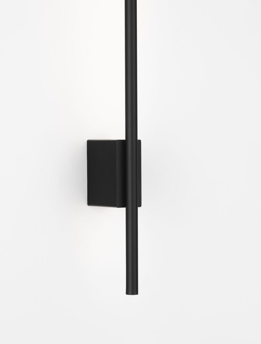 Applique murale noire vue de face, fine tige verticale sur support rectangulaire mat