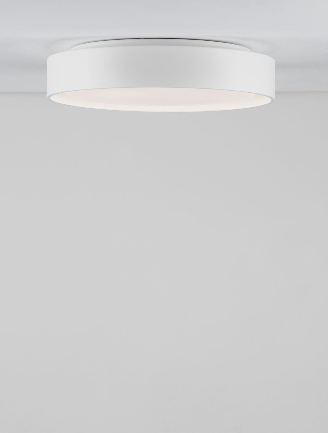 Vue de dessous du plafonnier blanc circulaire fixé au plafond, lumière allumée.