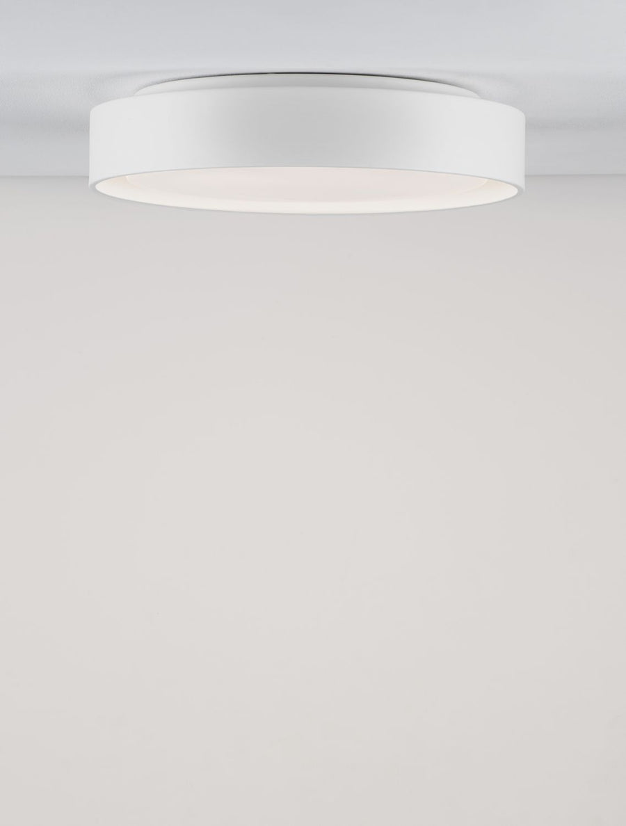 Vue en légère contre-plongée du plafonnier blanc fixé, halo lumineux périphérique visible.