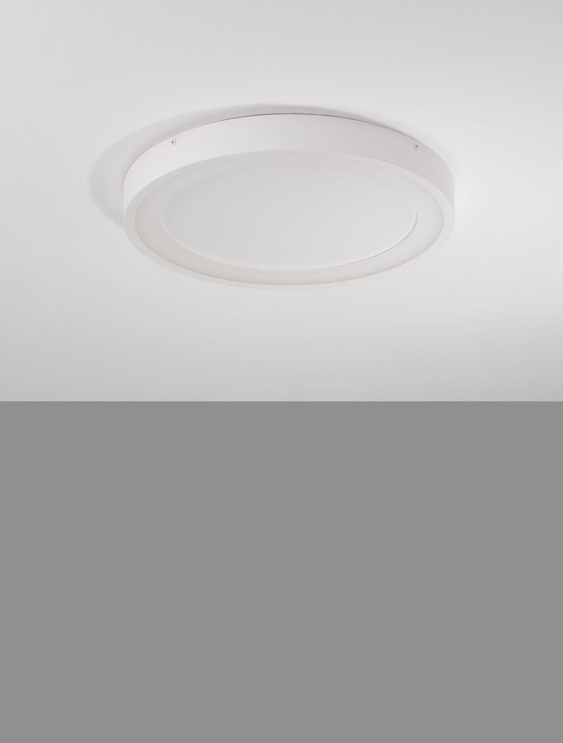 Plafonnier blanc éteint au plafond, diffuseur opalin et cerclage fin visible