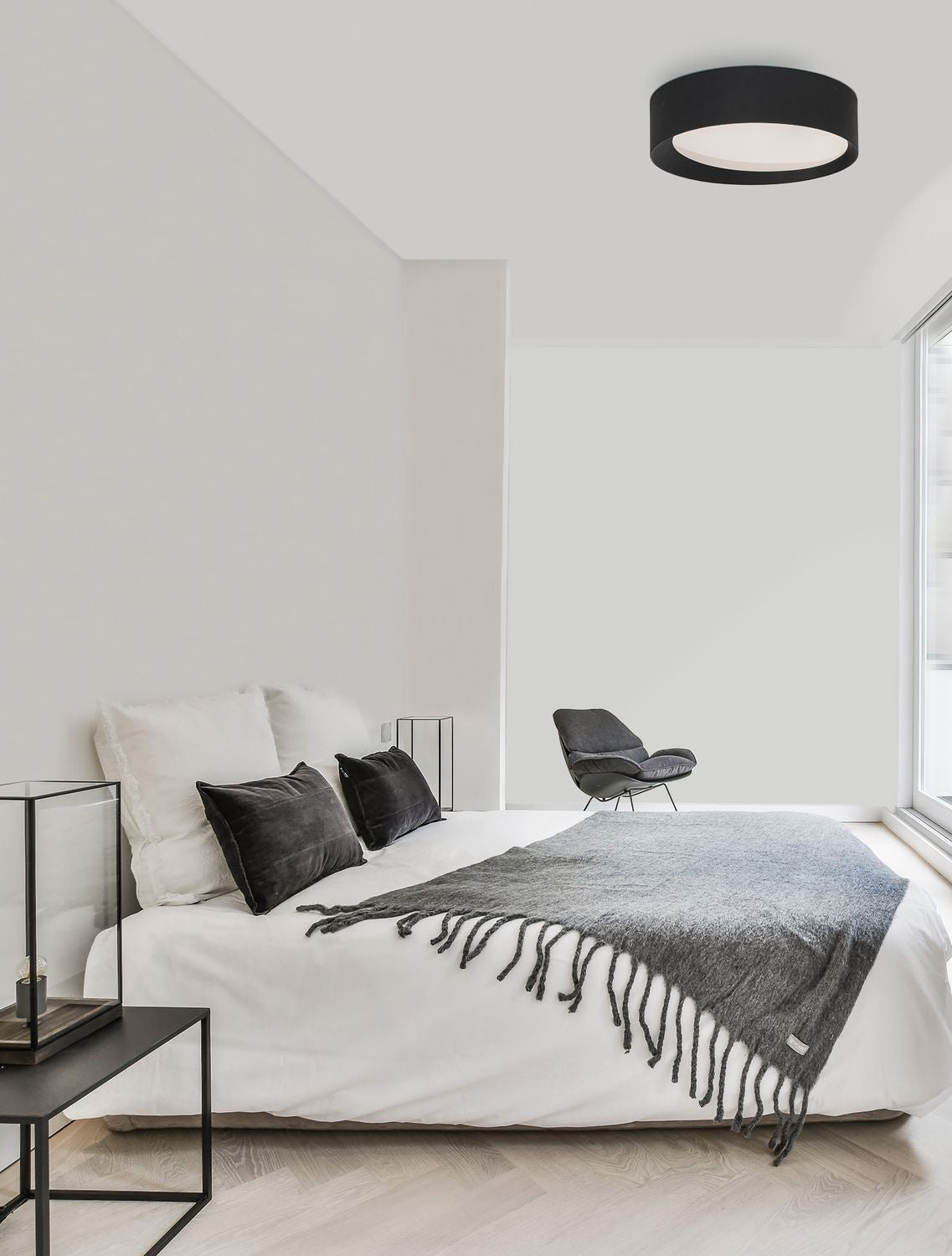 Plafonnier noir allumé au plafond d'une chambre blanche minimaliste