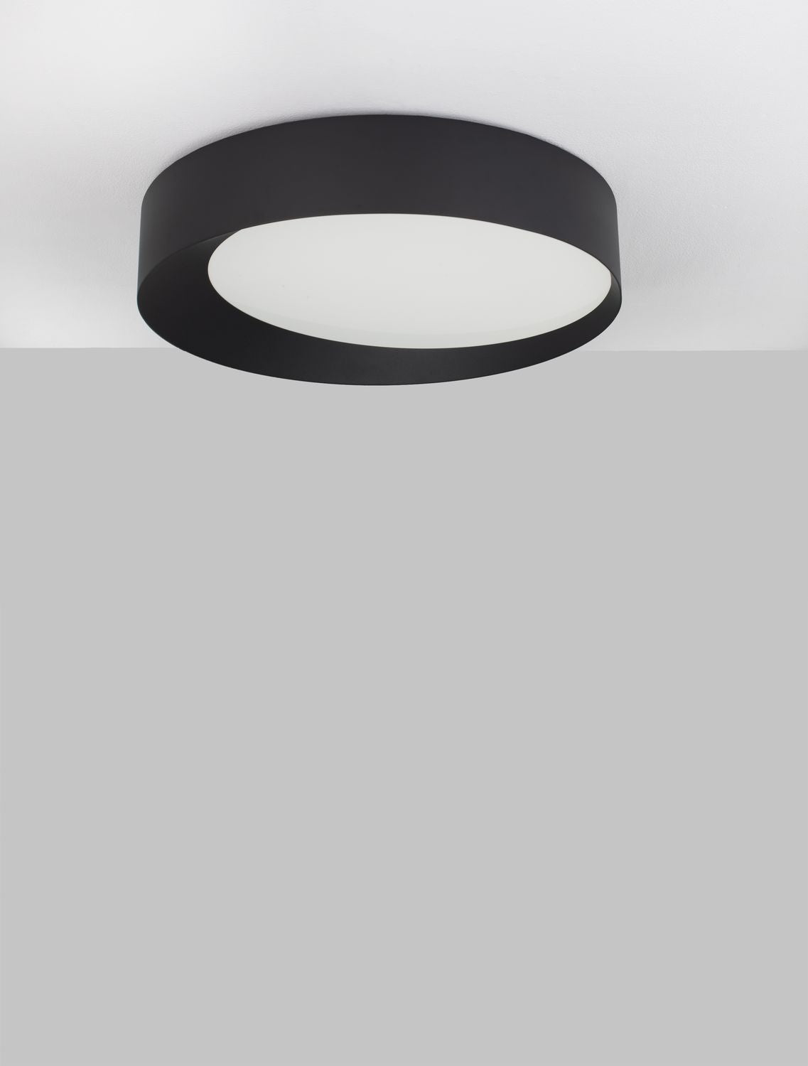 Plafonnier cylindrique noir fixé au plafond, vue de dessous montrant le diffuseur blanc