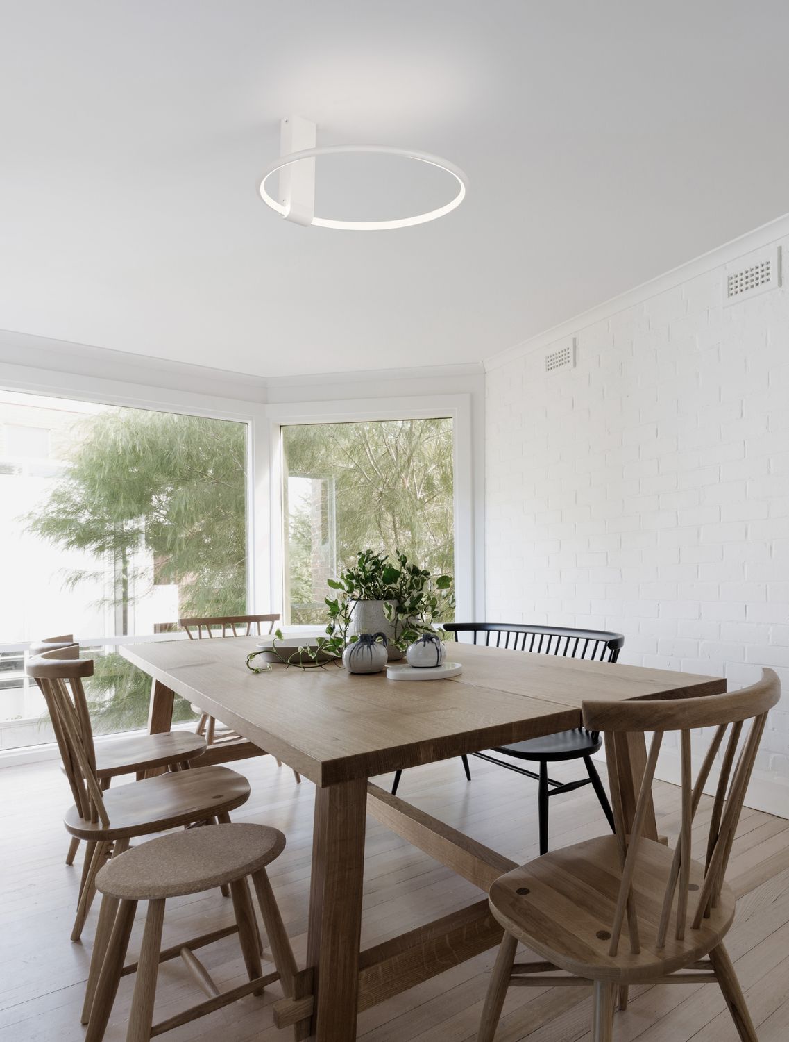 Suspension annulaire blanche suspendue au-dessus d'une table à manger en bois clair